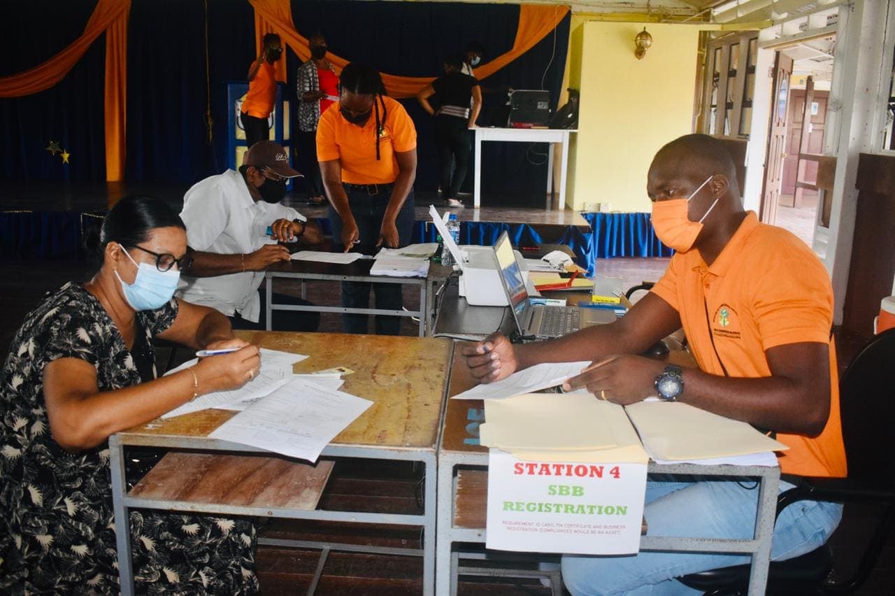 Small Business Bureau officers in orange shirts help business owners complete registration forms